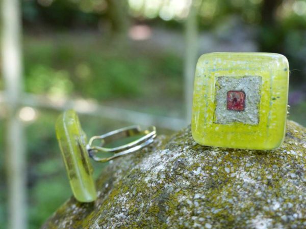 bagues en verre de couleurs verte posées sur pierre